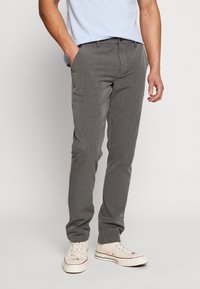 Gray dress pants with a slim fit, straight leg design, front pockets, and a zip fly, paired with white sneakers.