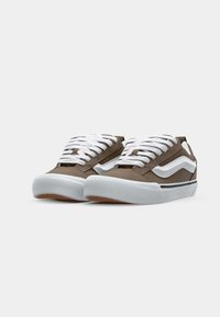 Braune Canvas-Sneaker mit weißen Schnürsenkeln und Streifenakzenten. Sie haben eine weiße Gummisohle und strukturierte braune Akzente im oberen Bereich.
