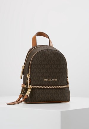 Kleiner dunkelbrauner Michael Kors Rucksack mit goldenen Reißverschlüssen und Logo, Ledergriff und MK-Monogramm-Muster auf weißer Oberfläche.