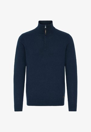 Tamsiai mėlynas megztinis su aukštu apykakle ir ketvirčio užtrauktuku. Rankogaliai ir apatinė dalis puošti rašto detalėmis, suteikiančiomis papildomo tekstūros.