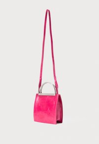 Borsa a tracolla in pelle di un vivace rosa con manici a doppio arco in metallo argentato, appesa su uno sfondo semplice.