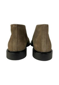 Stivaletti in suede marrone scuro con una finitura testurizzata, suola nera e dettagli di cucitura minimi, con una silhouette affusolata e liscia.