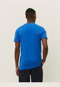 Royal blue bomull t-skjorte med korte ermer og rund hals. Glatt tekstur, avslappet passform og en litt forlenger bakhem.