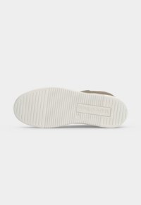 Semelle de chaussure avec rainures horizontales et le logo « Marc O'Polo » embossé près du talon sur une semelle extérieure en caoutchouc blanc.