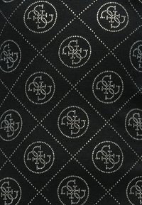 Μαύρο ύφασμα με μοτίβο ρόμβου διακοσμημένο με κυκλικά ασημί στρας, προσδίδοντας υφή και αντανακλαστική εμφάνιση.