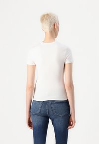 Hvit kortermet T-skjorte med en tettsittende passform, ribbet rund hals og glatt tekstur, parret med blå denimjeans.