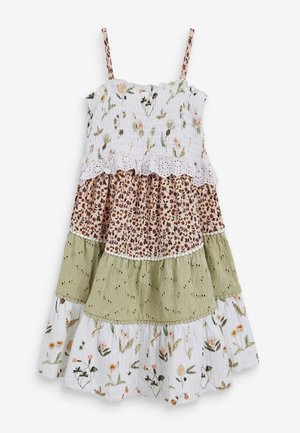 Robe sans manches à étages avec fines bretelles, comportant des couches à imprimé floral blanc et marron, œillets vert olive, et motifs botaniques blancs.
