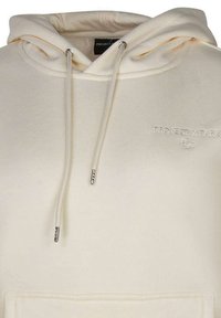 Hoodie couleur crème en tissu doux, doté d'une poche frontale, de cordons réglables et d'un logo en relief sur la poitrine.