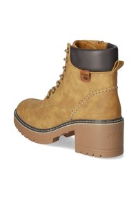 Tan leather ankle boot with a brown accent at the top, lace-up design, sturdy heel, and contrasting white stitching. Logo visible at the back.