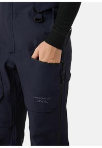 Marine waterdichte broek met een ritszak en geborduurd logo, met een gladde textuur en duurzame stof in een figuurgetailleerd ontwerp.