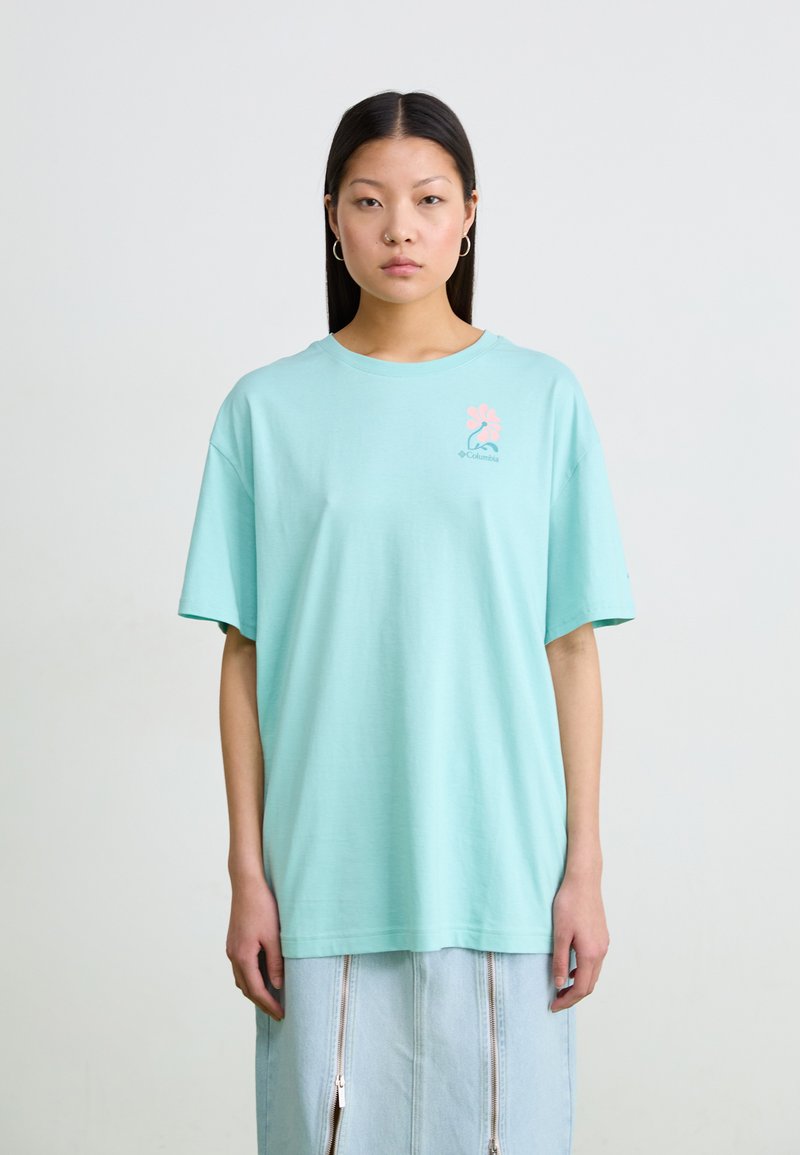 Tricou din bumbac verde mentă, cu mânecă scurtă, guler rotund și un design mic de logo roz pe partea stângă a pieptului.