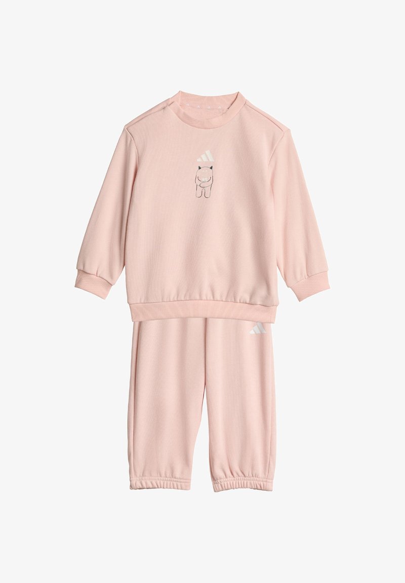 Ensemble de survêtement rose en deux pièces fait de tissu doux ; il présente des manches longues, des poignets élastiques et un petit motif imprimé sur le haut.