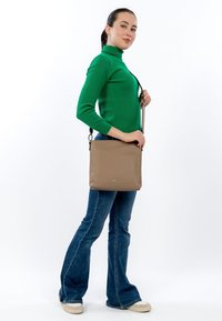 Beige leather crossbody bag with a smooth texture, featuring a rectangular shape, adjustable strap, and subtle logo detail on the front.