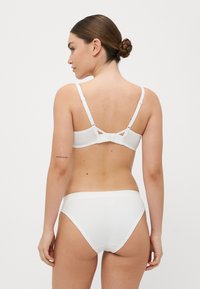 Hvit undertøysett med myk, glatt stoff og justerbare stropper, samt et enkelt, sømløst design. Bakutsikt fremhever minimal detaljering.