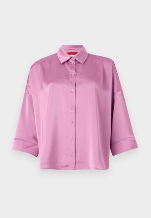 Camisa de satén rosa claro de botones con cuello, corte relajado y mangas enrolladas, que presenta una textura suave y un brillo sutil.