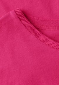 Fuchsiové bavlněné tričko s hladkou texturou a vroubkovaným kulatým výstřihem. Tkanina má jednotnou barvu bez vzorů nebo akcentů.