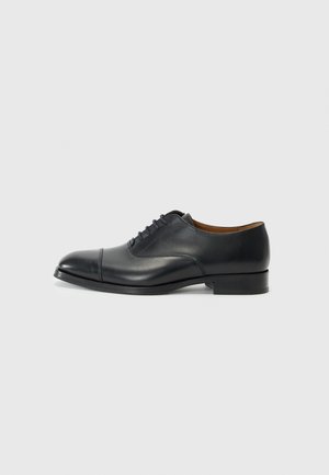 Scarpa da donna nera in pelle con finitura liscia, punta arrotondata, cinque passanti per i lacci e tacco basso a blocco. Design minimalista con cuciture sottili.
