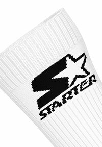 Calzino bianco a coste con un logo a stella nera e la parola "STARTER" lavorata sotto il logo.