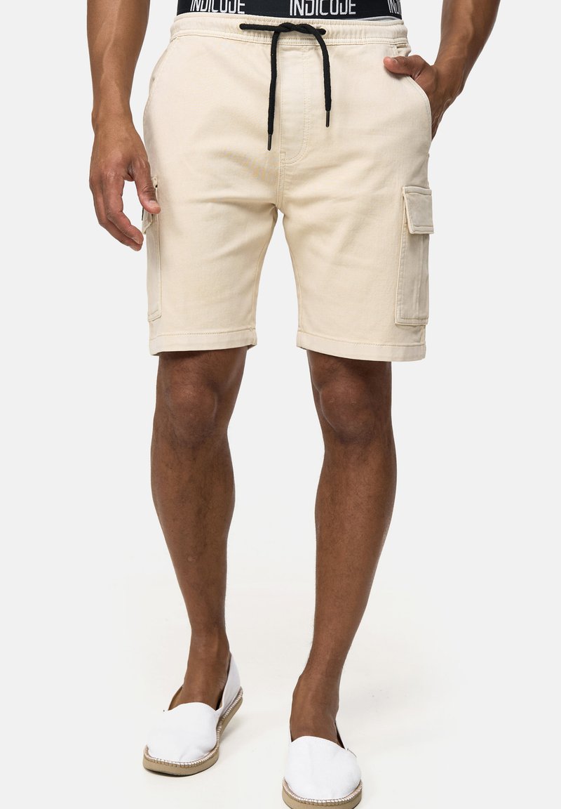 Pantalones cortos cargo color beige, hechos de algodón, con una cintura ajustable con cordón, bolsillos laterales y un ajuste holgado, con un acabado texturizado.
