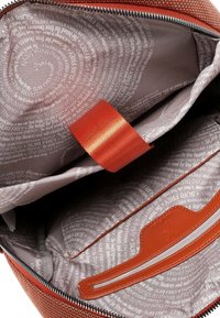 Rode stoffen tas binnenkant met een gladde, patroonvoering met grijze tekstkrullen. Inclusief een textuurige oranje band en een organisatorisch vak.