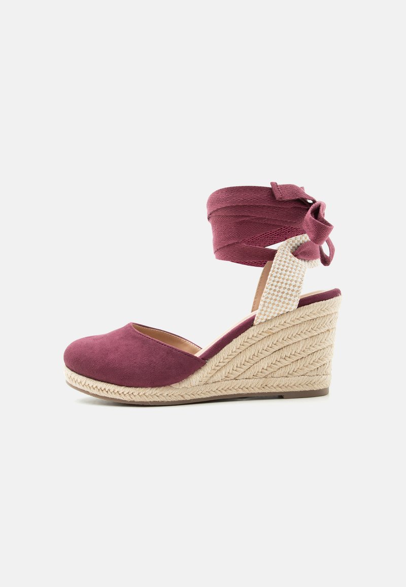 Chaussure espadrille compensée avec semelle en jute tressée, bout fermé en daim bordeaux et lien assorti à nouer autour de la cheville sur fond blanc.