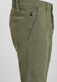 Pantalons kaki en tissu mélangé de coton résistant, avec une coupe droite, des poches latérales et des détails de couture contrastés.