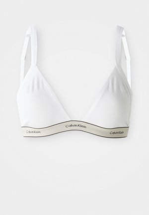White Calvin Klein soft triangle bra with adjustable straps and branded elastic band under bust on plain background.