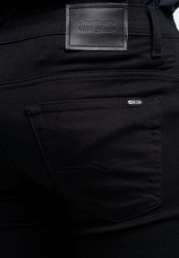 Los jeans de mezclilla negra presentan una etiqueta de cuero en la cintura con "BIG STAR", costuras curvas en el bolsillo trasero y una textura elegante.