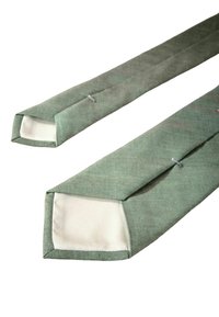 Grønne cylindriske puder med firkantede ender, der har en tekstureret overflade og kontrasterende beige inderside. Syede kanter med to synlige lukninger.