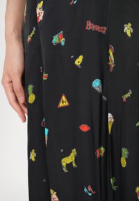 Schwarzer Stoff mit bunten kleinen Drucken, darunter Banane, Zebra, Lippen, Eistüte, Ananas, Papagei und "Fiorucci"-Text.