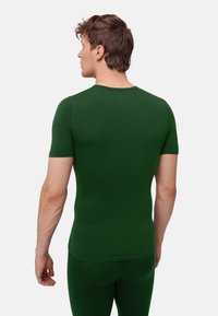 Figursydd kortärmad skjorta i mörkgrön färg, tillverkad av texturerat material, med rund halsringning och sömlösa axlar.