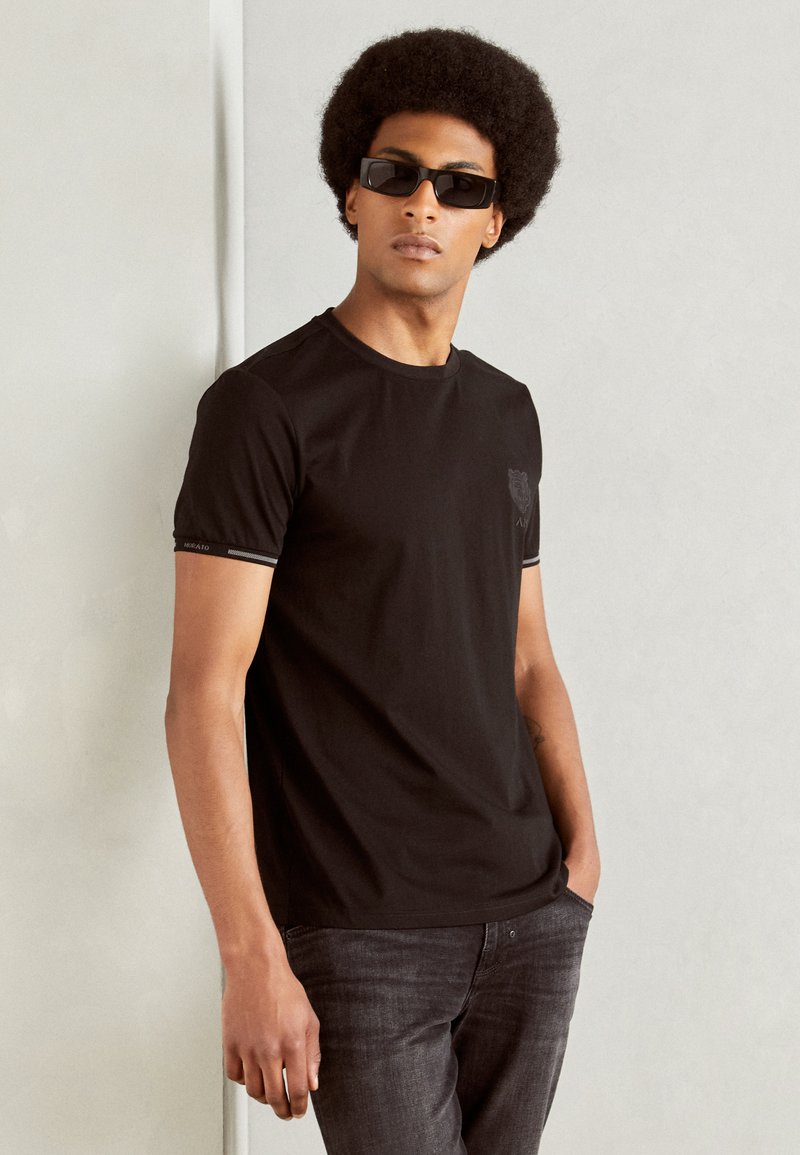 Zwart katoenen T-shirt met korte mouwen, voorzien van een subtiele logo op de borst en contrasterende bies rond de halslijn en mouwen.