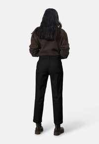 Zwarte geribde broek met een hoge taille, voorzien van zijzakken en een rechte pasvorm, gecombineerd met een cropped, donkerbruin langemouwen top.