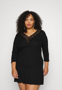 Vestido preto com mangas três quartos, bainha em forma de onda e um decote em V profundo, apresentando detalhes em renda preta ao longo da gola.