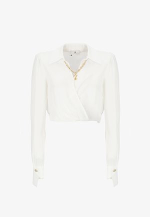 Blusa bianca a maniche lunghe, corta, realizzata in un tessuto liscio con un design avvolgente. Presenta una collana in catena dorata e accenti con bottoni a contrasto.