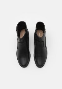 Czarne skórzane botki za kostkę o eleganckim designie, z bocznymi suwakami i teksturowaną gumową podeszwą. Gładkie wykończenie z minimalnymi akcentami.