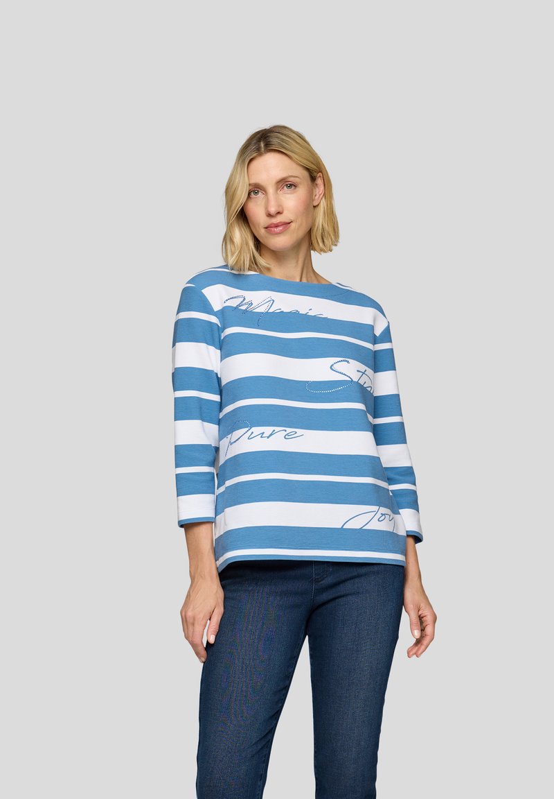 Blau-weißer gestreifter Langarmoberteil mit einem runden Halsausschnitt und dekorativen Textakzenten. Der Stoff wirkt weich und leicht. Kombiniert mit dunklen Jeans.