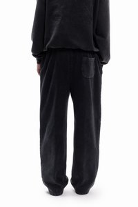 Pantalones jogger de algodón negro con un corte relajado, bolsillos laterales y un único bolsillo trasero. Textura suave, acabado liso con un patrón sólido.