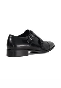 Black leather dress shoe with rounded toe and two adjustable buckle straps. Smooth texture, low stacked heel, and detailed stitching.