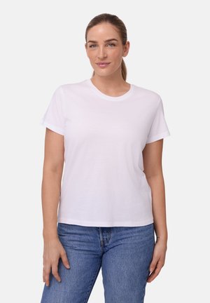 Weißes Baumwoll-T-Shirt mit kurzen Ärmeln, rundem Ausschnitt und lockerem Schnitt. Kombiniert mit blauen Jeans. Glatte Textur, keine Muster.