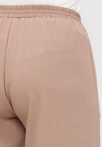Light pink loungewear pants with an elastic waistband, made from soft, textured fabric, showcasing a relaxed fit and simple design.
