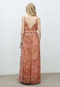 Vestido maxi con espalda en V, que presenta un patrón de paisley en cálidos tonos de rosa y naranja. Hecho de una tela ligera, con tirantes ajustables.