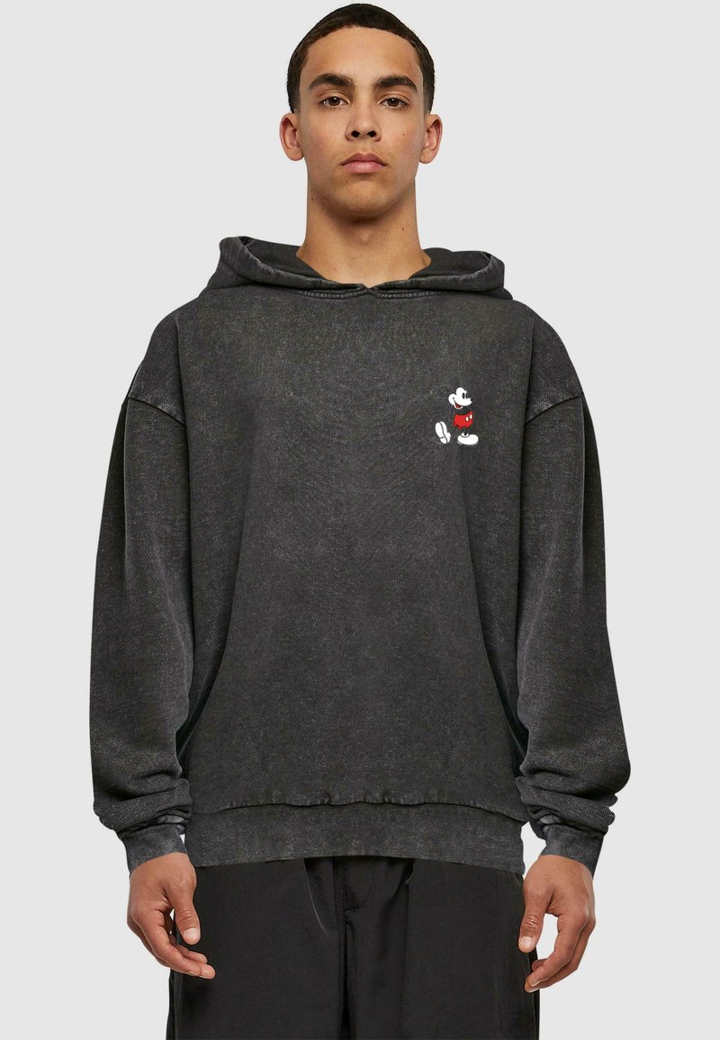 Czarna bluza z kapturem wykonana z miękkiego materiału w luźnym kroju, z małym białym grafiką Myszki Mickey na piersi. W komplecie sznurek do regulacji kaptura.