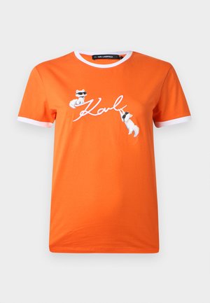 Camiseta de algodón naranja con ribetes blancos, que presenta dos personajes de dibujos animados y la firma "Karl" en una tipografía estilizada en el frente.