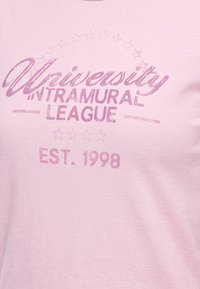 Розова тъкан с избледнял лилав текст, гласящ "University Intramural League Est. 1998", и декоративни звезди над и под текста.