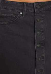 Gonna in denim nero con design a bottoni sul davanti, cinque bottoni, fascia in vita classica e texture liscia.