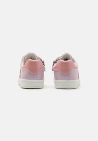 Des baskets synthétiques roses présentent une finition lisse, un embout rond, une semelle en caoutchouc blanche et des accents de talon rose clair contrastants.