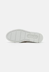 Suela de zapato con un material de goma blanca texturizada, un patrón de agarre segmentado y un logo en relieve en el lateral.