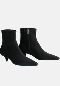 Čierne semišové členkové čižmy s špicatými špičkami, minimálnym zipsovým detailom na jednej strane a nízkym vrstveným podpätkom, so hladkou textúrou.