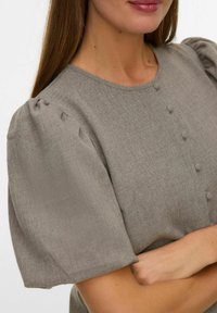 Sivi top od mješavine lana s kratkim naboranim rukavima, okruglim izrezom i tri ukrasna gumba sprijeda. Ugladak s teksturiranim materijalom.